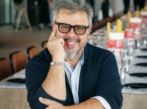 Donato de Santis cocinando en un evento gastronómico, vestido con chaqueta blanca y rodeado de ingredientes frescos italianos.
