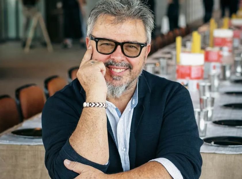 Donato de Santis cocinando en un evento gastronómico, vestido con chaqueta blanca y rodeado de ingredientes frescos italianos.