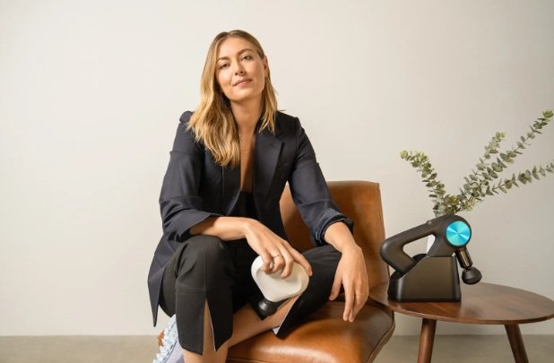 Maria Sharapova celebrando un punto en una cancha de tenis durante un torneo de Grand Slam, vistiendo ropa deportiva blanca y empuñando su raqueta.