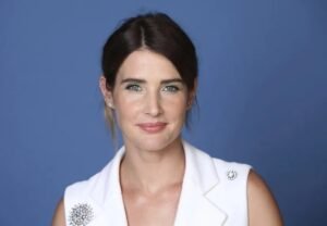 Cobie Smulders en una alfombra roja, vestida de gala, sonriendo a cámara